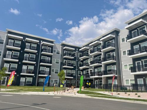 Apartments in Clearfield UT Modern four-story apartment building with balconies, set against a blue sky. Colorful flags and balloons decorate the landscape.